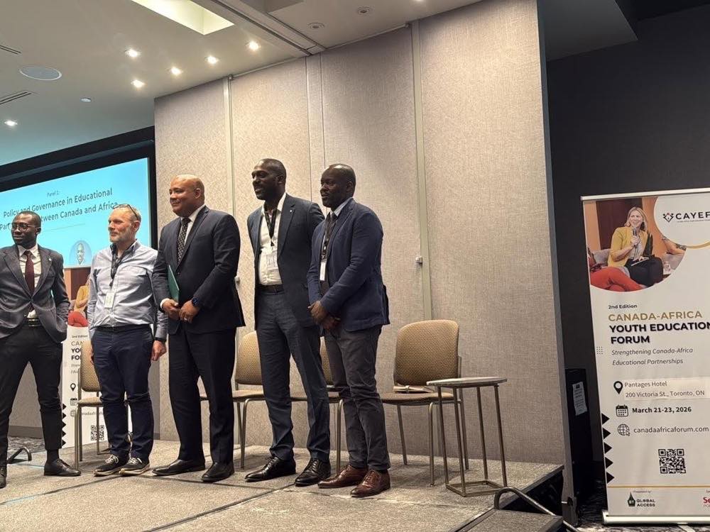 Five panellists stand at the front of a conference room. A screen behind them reads “Panel 1: Policy and Governance in Educational Partnerships between Canada and Africa”, and a banner at the right advertises the forum’s second edition at the Pantages Hotel, Toronto.