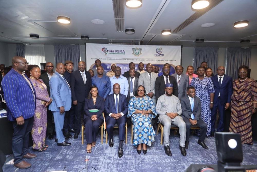 Une trentaine de délégués en tenue de ville posent pour une photo de groupe dans une salle de conférence, cinq d’entre eux assis au premier rang. La toile de fond porte les emblèmes de HaPSNA, de la Côte d’Ivoire et de HeDPAC au-dessus de la mention « Partenariat Sud-Sud pour l’excellence dans les domaines de la santé et de la fonction publique ».