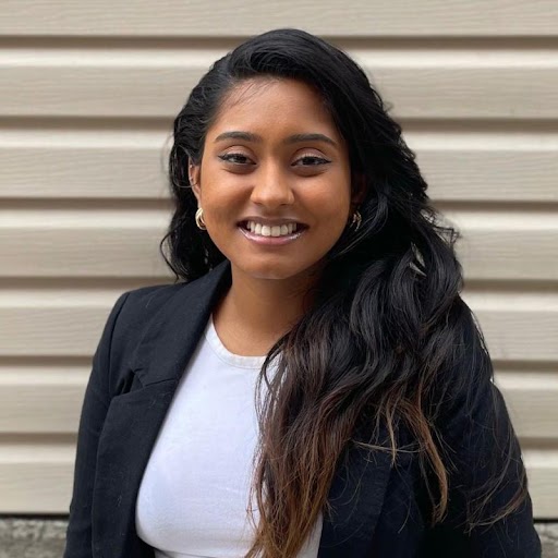 Osuri Embulgamage, in a black blazer over a white top, photographed outdoors.
